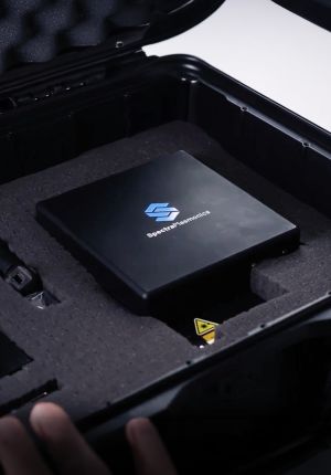 A black SpectraPlasmonics handheld analyzer seated in custom foam inside an open protective hard case.